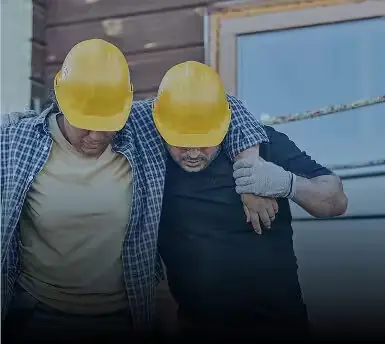 Injured worker in a hard hat being helped by a coworker