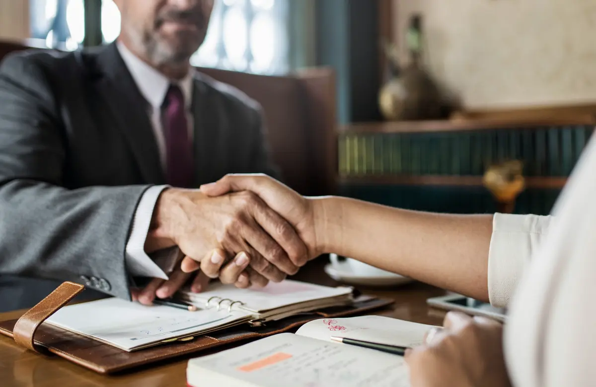 Attorney shaking hands with a client across a desk